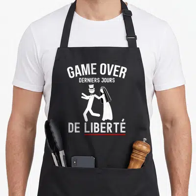 Tablier de cuisine noir avec texte Game Over Derniers Jours De Liberté et silhouettes couple en tenue nuptiale.