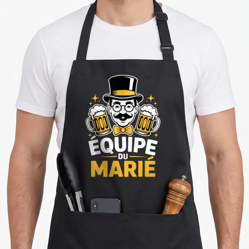 Tablier de cuisine noir avec illustration d'un homme moustachu en chapeau haut de forme tenant deux bières, texte équipe du marié.
