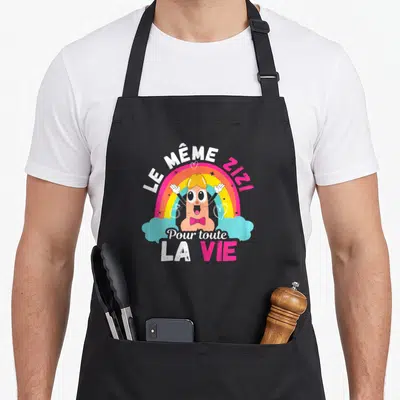 Tablier de cuisine noir avec un ver de terre rose sous un arc-en-ciel et le texte Le même Zizi pour toute la vie.