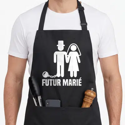 Tablier de cuisine noir avec une silhouette blanche d'un couple enchaîné et le texte futur marié imprimé en bas.