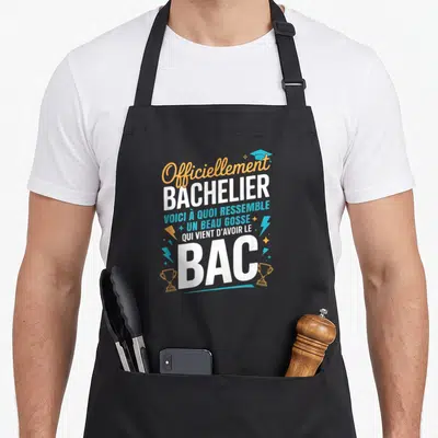 Tablier de cuisine noir avec texte « Officiellement Bachelier » et illustrations de trophées dorés.