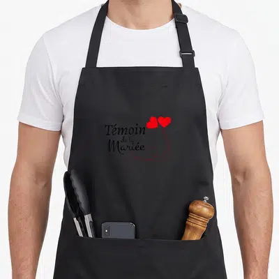 Tablier de cuisine noir avec linscription Témoin de la Mariée et deux cœurs rouges en ballon.