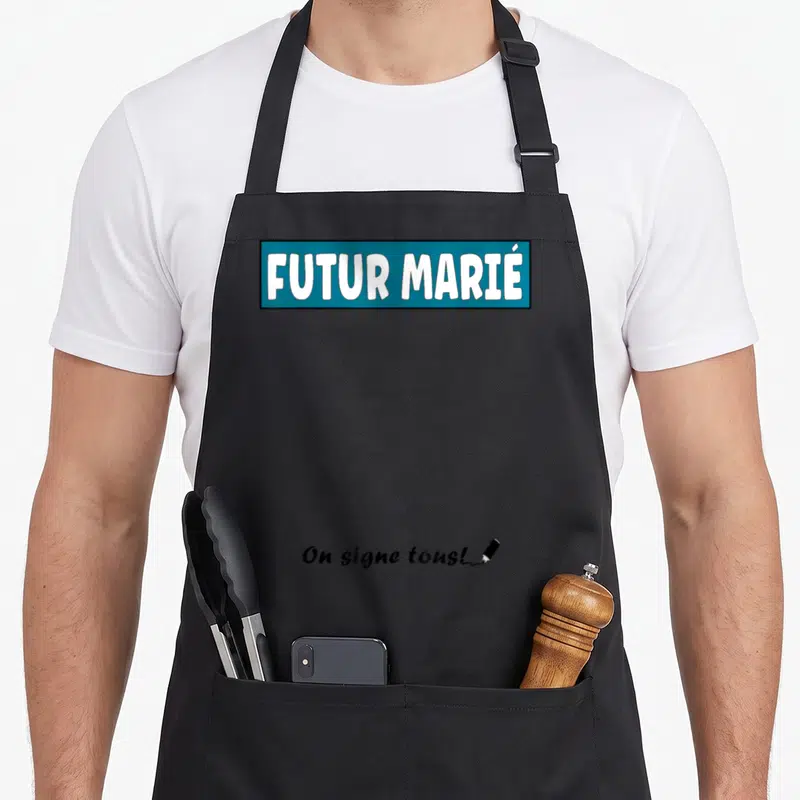 Tablier de cuisine noir avec inscription Futur Marié dans un cartouche bleu et la phrase On signe tous en bas à droite.
