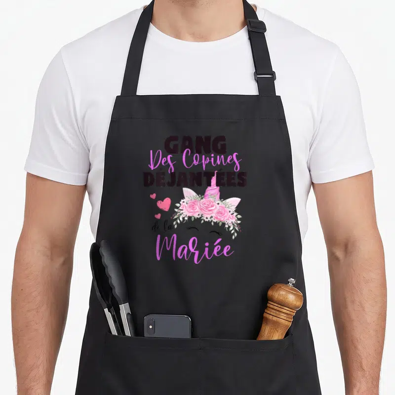 Tablier de cuisine noir avec inscription Gang des copines déjantées de la mariée et illustration de licorne fleurie rose.