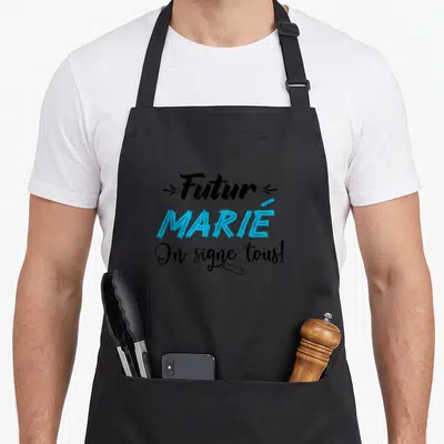 Tablier de cuisine noir avec inscription Futur Marié On signe tous et dessin de marqueur bleu.