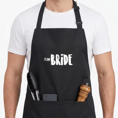 Tablier de cuisine noir avec l'inscription Team Bride en lettres blanches stylisées au centre.