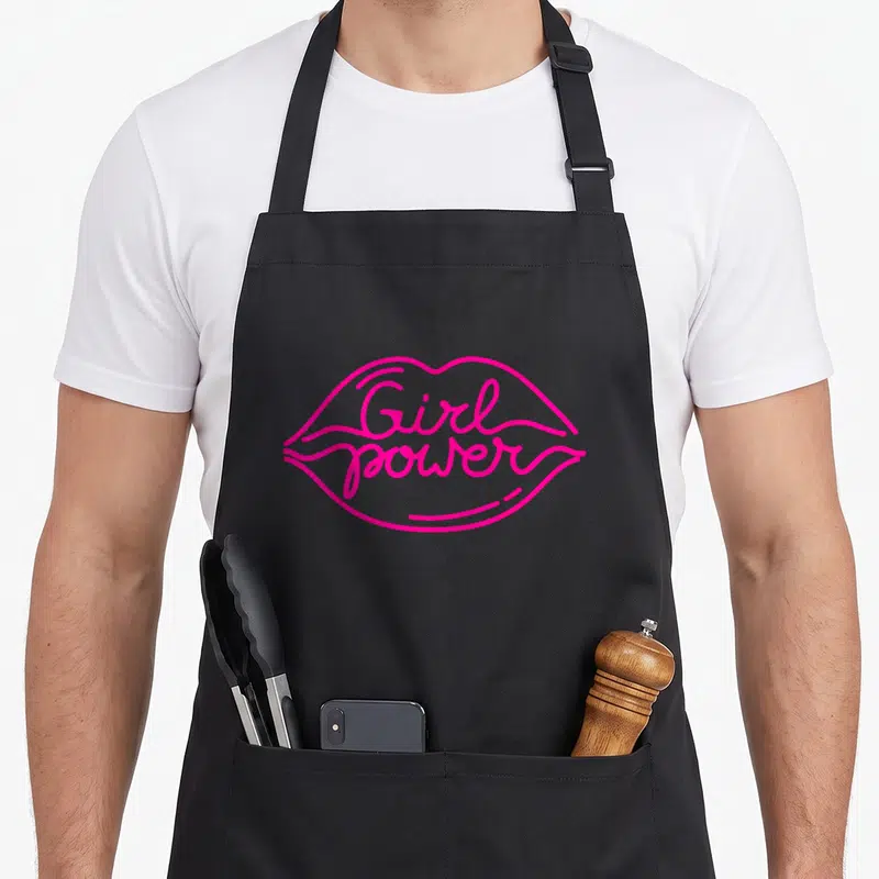 Tablier de cuisine noir avec illustration lèvres roses et texteGirl power en écriture cursive.