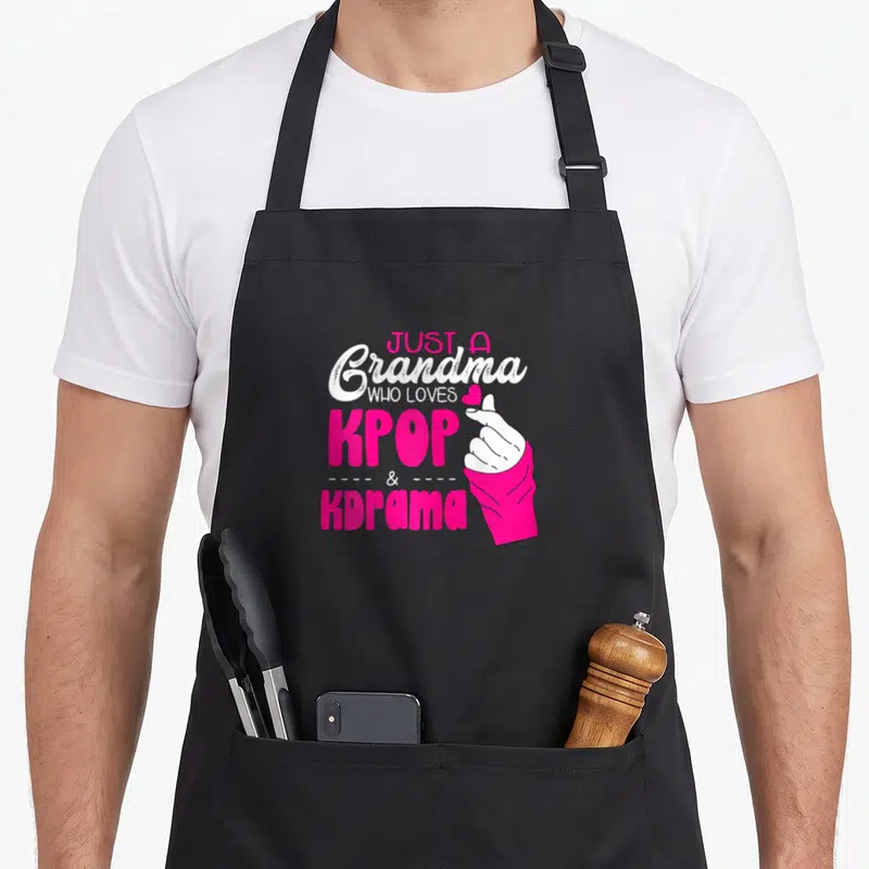 Tablier de cuisine noir avec inscription Just A Grandma Who Loves Kpop And Kdram et main faisant un cœur en rose vif.