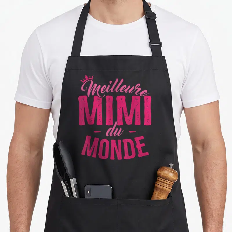 Tablier de cuisine noir avec l'inscription rose Meilleure Mimi du Monde surmontée d'une couronne.