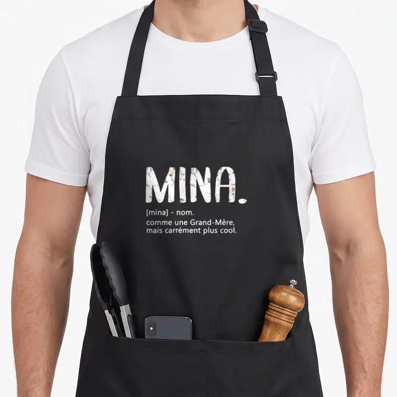Tablier de cuisine noir avec l'inscription Mina comme une Grand-Mère mais carrément plus cool en typographie blanche.