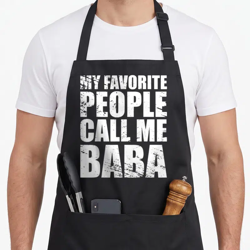 Tablier de cuisine noir avec le texte MY FAVORITE GENS CALL ME BABA en lettres blanches capitales.