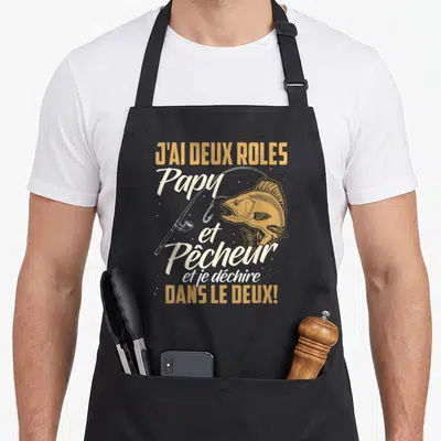 Tablier de cuisine noir avec illustration de perche, canne à pêche et texte J'ai deux rôles Papy et Pêcheur.