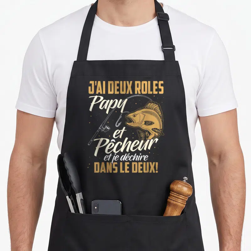 Tablier de cuisine noir avec illustration de perche, canne à pêche et texte J'ai deux rôles Papy et Pêcheur.