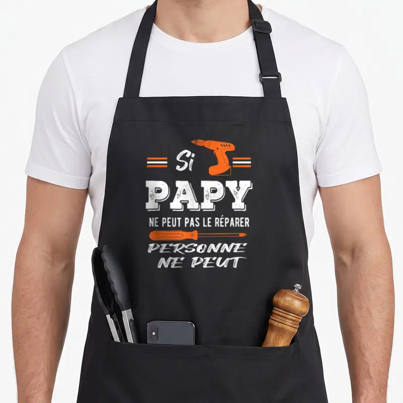 Tablier de cuisine noir avec une perceuse orange et le texte Si Papy ne peut pas le réparer personne ne peut en blanc.