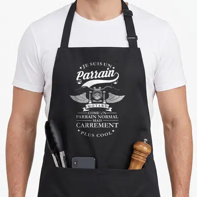 Tablier de cuisine noir avec motif blanc Je suis un Parrain Motard Carrement Plus Cool illustré d'une moto à ailes.