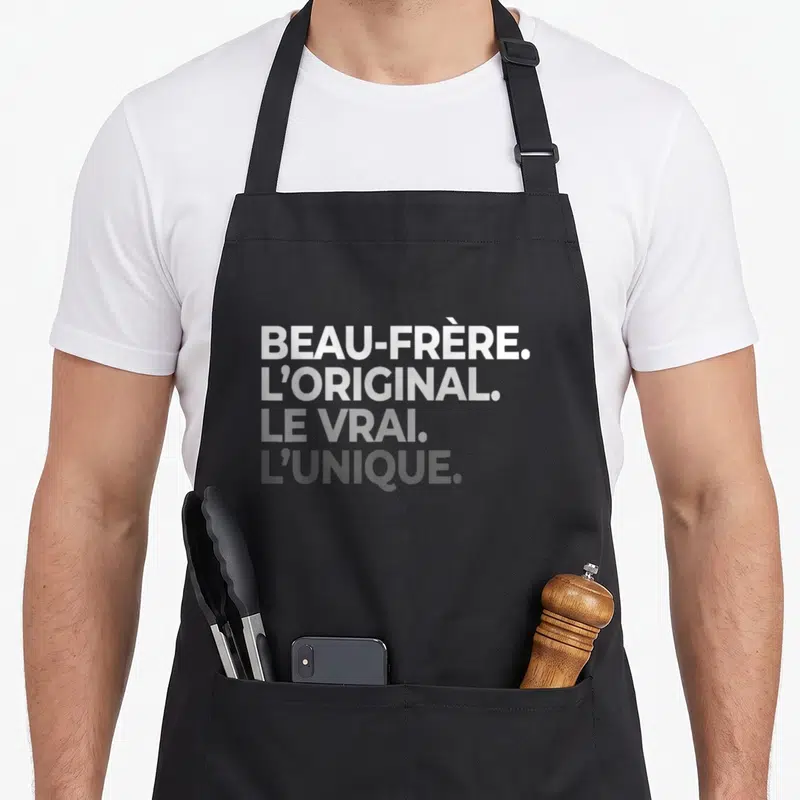 Tablier de cuisine noir avec texte blanc BEAU-FRÈRE LORIGINAL LE VRAI LUNIQUE imprimé en typographie dégradée.