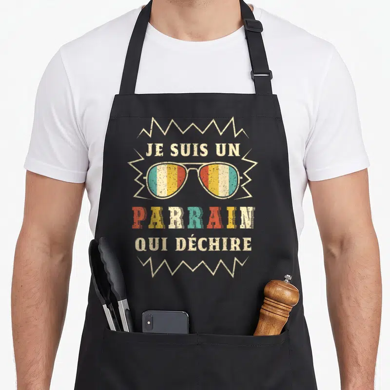 Tablier de cuisine noir avec inscription Je suis un parrain qui déchire et lunettes de soleil multicolores.