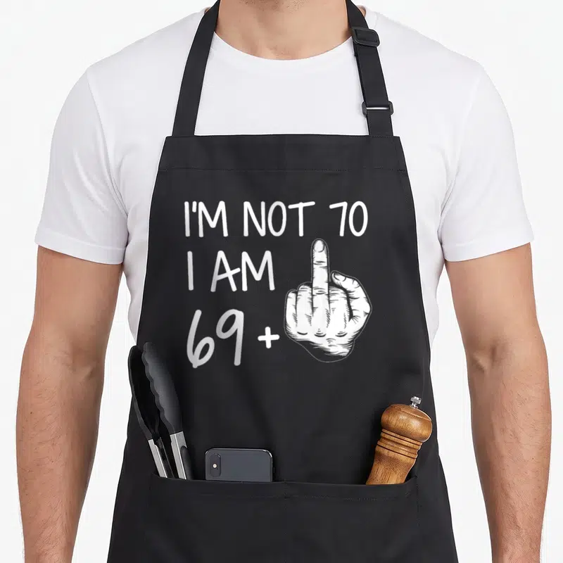 Tablier de cuisine noir avec inscription blanche Im Not 70 I Am 69 Plus et illustration de main levée.