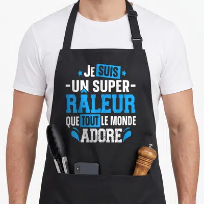 Tablier de cuisine noir avec l'inscription Je suis un super râleur que tout le monde adore en bleu et blanc.