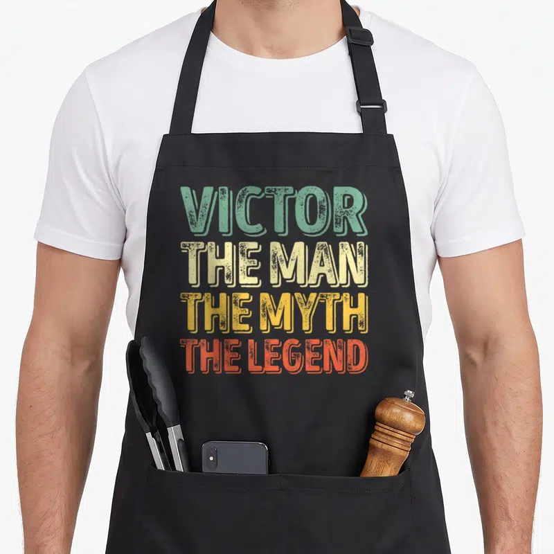 Tablier de cuisine noir avec l'inscription Victor The Man The Myth The Legend en lettres délavées multicolores.