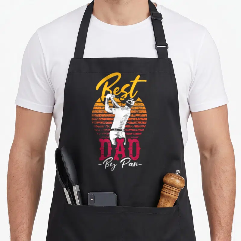 Tablier de cuisine noir avec illustration d'un golfeur et le texte Best Dad By Pan en couleurs vives.