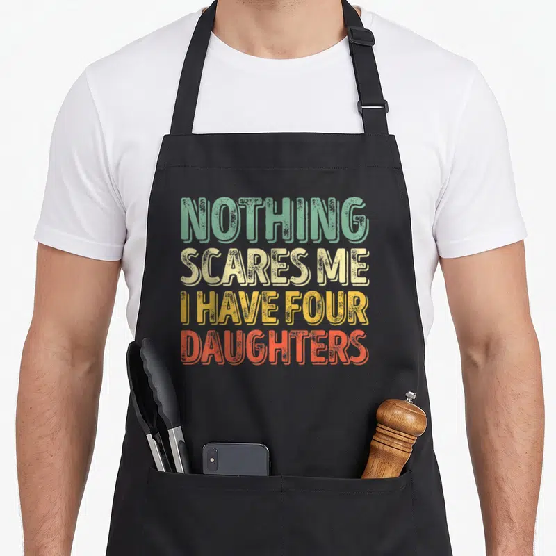 Tablier de cuisine noir avec inscriptionNothing Scares Me I Have Four Daughters en lettres dégradées vintage.