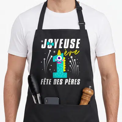 Tablier de cuisine noir avec le chiffre 1 monstre turquoise, nœud papillon et texte Joyeuse 1ère fête des pères.