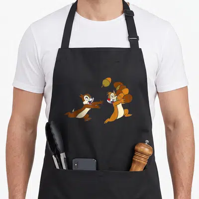 Tablier de cuisine noir avec Chip et Dale courant pour attraper une noisette volante.