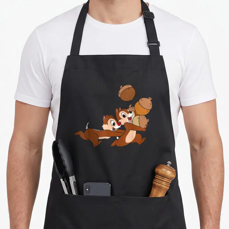 Tablier de cuisine noir avec Chip et Dale courant avec des noix imprimés au centre.