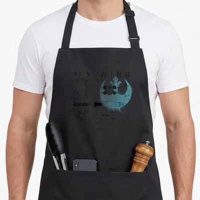 Tablier de cuisine noir avec schéma technique du vaisseau T-65 X-Wing Starfighter en lignes noires et accents bleu clair.