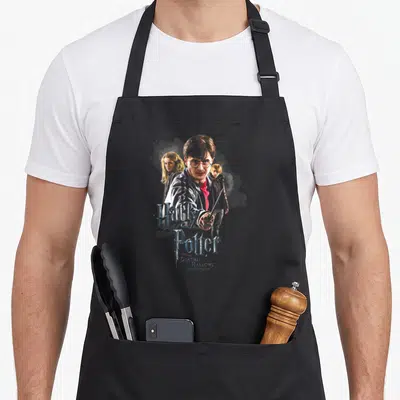 Tablier de cuisine noir avec illustration de Harry Potter, Ron et Hermione tenant des baguettes magiques.