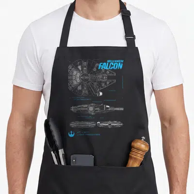 Tablier de cuisine noir avec le dessin technique en bleu du vaisseau spatial et l'inscription MILLENIUM FALCON en haut à droite.