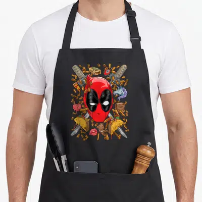 Tablier de cuisine noir avec masque Deadpool, tacos, pizza, cartouches et sabres croisés.
