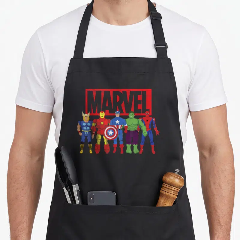 Tablier de cuisine noir avec illustration des Avengers en figurines d'action sous le logo Marvel rouge et gris.