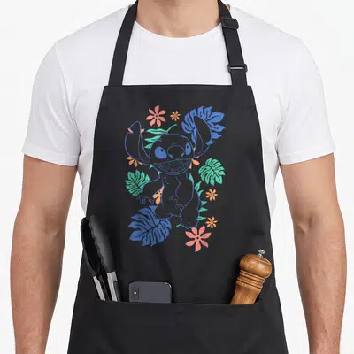 Tablier de cuisine noir avec Stitch floral outline entouré de fleurs roses et de feuilles vertes et bleues.