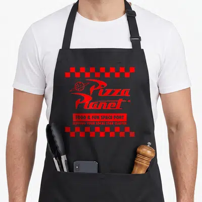 Tablier de cuisine noir avec logo Pizza Planet rouge, bandes de damiers et texte Food Fun Space Port.