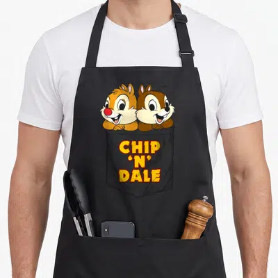 Tablier de cuisine noir avec Chip et Dale sortant d'une poche imprimée en couleur.