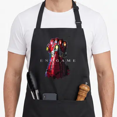 Tablier de cuisine noir avec illustration du gant d'Iron Man et le texte Endgame en blanc au centre.