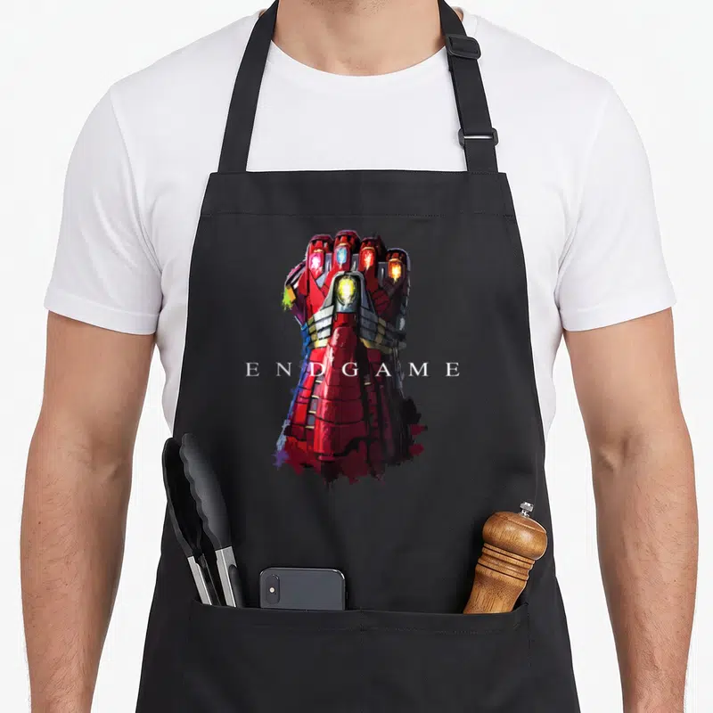 Tablier de cuisine noir avec illustration du gant d'Iron Man et le texte Endgame en blanc au centre.