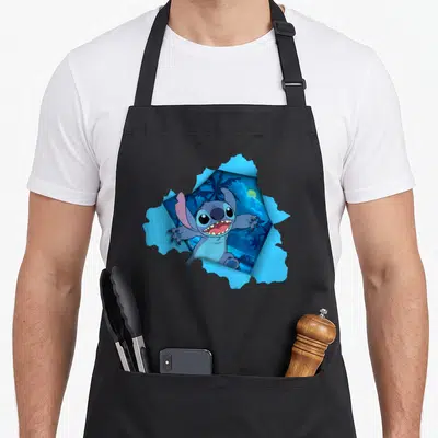 Tablier de cuisine noir avec Stitch qui sort d'une déchirure bleue sur fond de nuit tropicale.