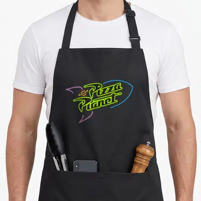 Tablier de cuisine noir avec le logo Pizza Planet en lettres noires et vertes, entouré d'une orbite bleue et d'un petit astre orange.