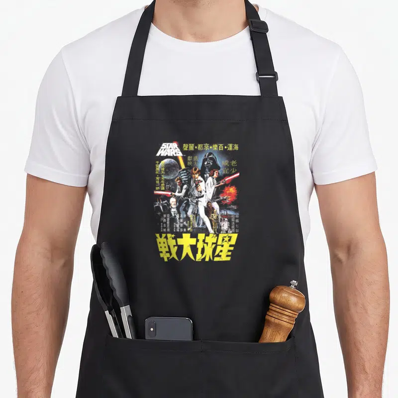 Tablier de cuisine noir avec une illustration colorée style affiche de film chinoise représentant des personnages de science-fiction et du texte en caractères jaunes.