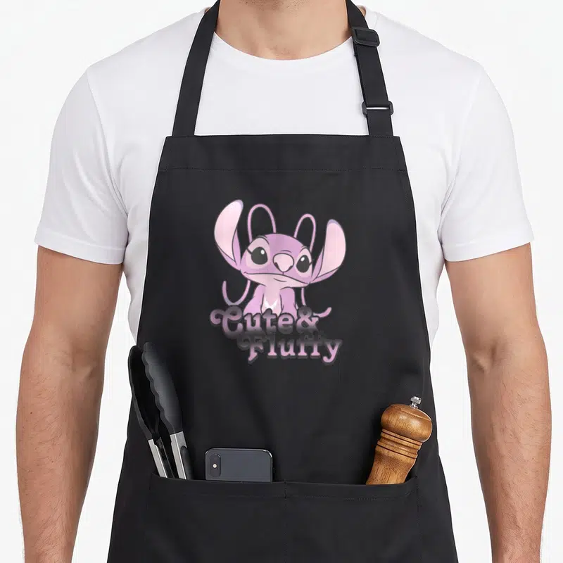 Tablier de cuisine noir avec un alien rose aux grands yeux et le texte « Mignon & Moelleux » imprimé au centre.