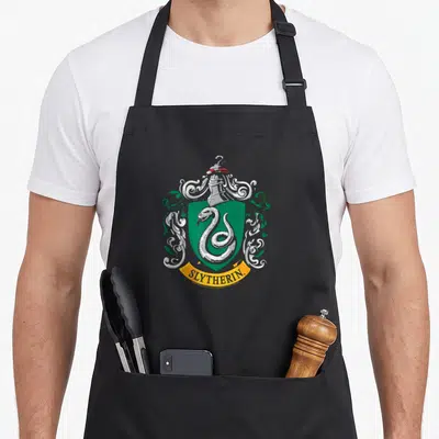 Tablier de cuisine noir avec le blason de la maison Serdaigle, un serpent argenté sur fond vert et une bannière jaune.