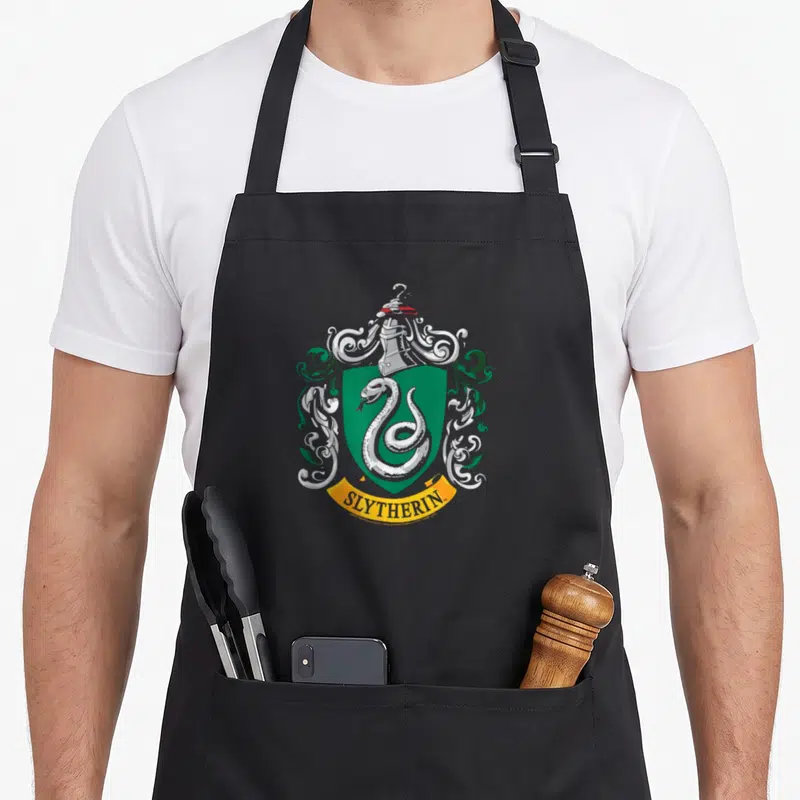 Tablier de cuisine noir avec le blason de la maison Serdaigle, un serpent argenté sur fond vert et une bannière jaune.