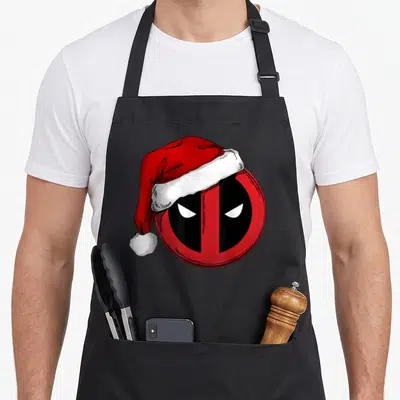 Tablier de cuisine noir avec logo Deadpool icon coiffé d'une casquette de Père Noël rouge et blanche.