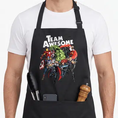 Tablier de cuisine noir avec illustration de super-héros et texte Team Génie en lettres blanches.