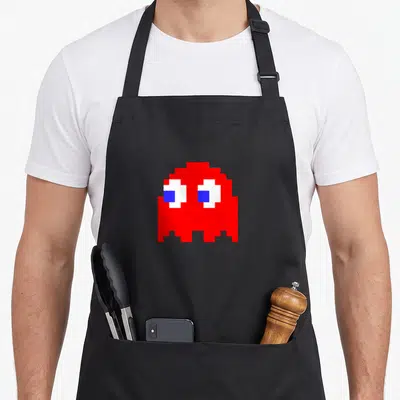Tablier de cuisine noir avec un fantôme rouge pixelisé aux yeux bleus et blancs, style jeu vidéo rétro.