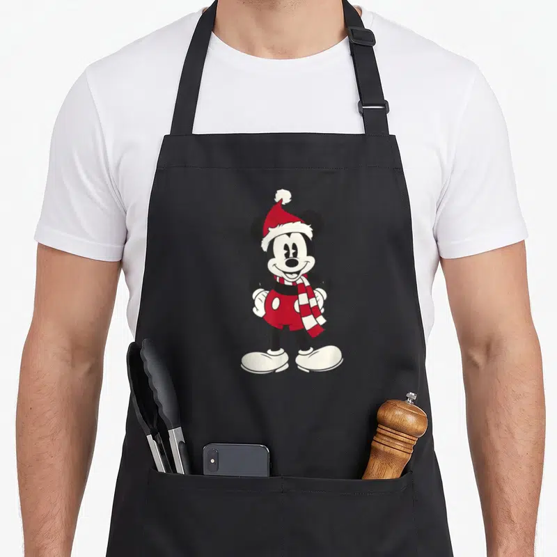 Tablier de cuisine noir avec un portrait de Mickey Mouse Classic portant une bonnet rouge et un foulard à carreaux.