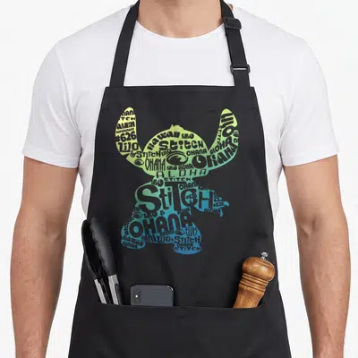 Tablier de cuisine noir avec silhouette de Stitch composée des mots Ohana, Aloha et Lilo en couleurs dégradées.